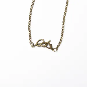 Dettaglio ravvicinato di una collana a catena in bronzo antico con chiusura a moschettone.