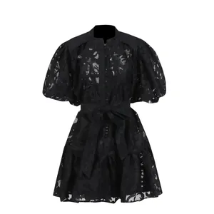 Detail view of a black hollow jacquard dress with puff sleeves and tie waist belt