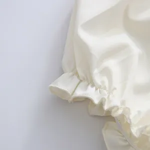 Detailansicht der cremefarbenen Puffärmel-Manschette mit elastischem Rüschen-Besatz.
