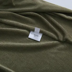 Close-up of 100% polyester wash label on green pleated fabric