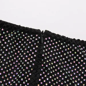 Macro view of iridescent rhinestones on black mesh fabric with invisible zipper detail
