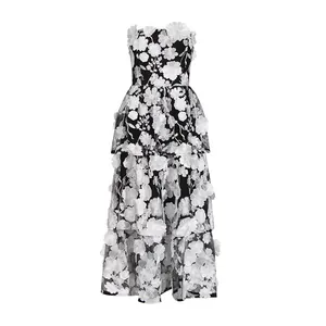 Elegant black strapless maxi dress with 3D white floral embroidery and tiered skirt design.