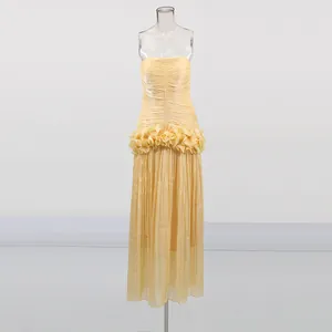 Detailed view of a yellow strapless maxi dress featuring a ruffled waist and pleated skirt.