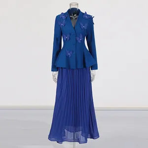 Détail d'un ensemble deux pièces bleu avec veste papillon 3D et jupe plissée