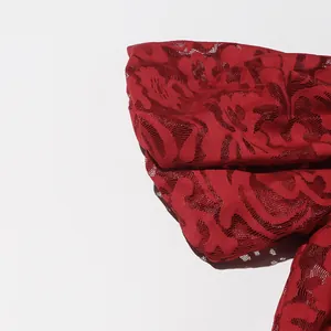 High-resolution close-up of elegant red hollow jacquard lace fabric with floral patterns