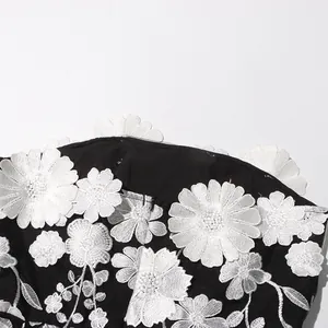 Close-up of white 3D floral embroidery on a sexy black strapless tube top long dress detail.