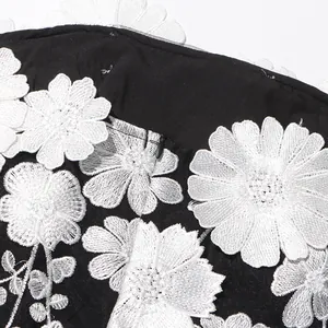 Close-up of intricate white flower embroidery and invisible zipper on black dress