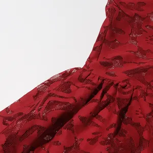 Macro close-up detail showing the intricate red hollow-out floral jacquard fabric on a dress