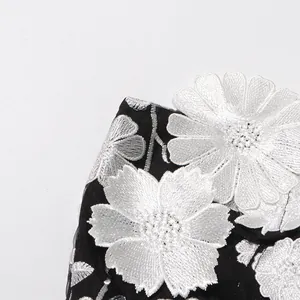 Close-up view of the white 3D floral embroidery detail on this black elegant dress