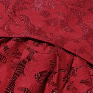 Macro close-up of intricate red hollow jacquard fabric texture on a stylish spring dress