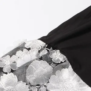 Close-up detail of white 3D floral embroidery on black mesh fabric for elegant evening dress
