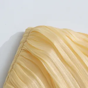 Detailed macro view of the pleated fabric and texture on a yellow strapless dress detail.