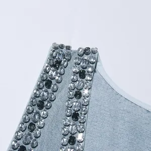 Dettaglio ravvicinato delle decorazioni in strass di cristallo sulla spallina di un abito di denim