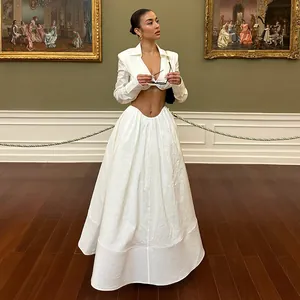 Elegant white two-piece set with V-neck cropped top and long maxi skirt in a museum setting.