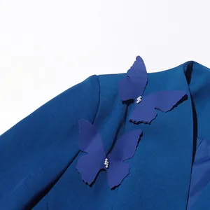 Vue détaillée d'un blazer bleu élégant avec des papillons 3D décoratifs et des perles.