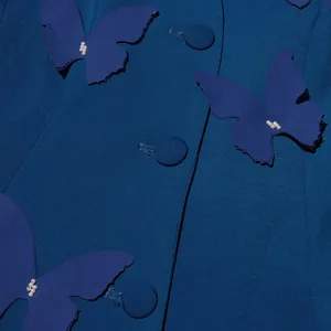Détail d'appliqués papillons 3D avec perles sur une veste de style français bleu canard