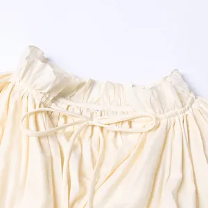 Vue détaillée du col à volants et du nœud papillon sur une robe longue de style vacances crème