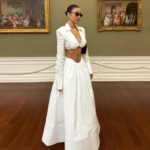 Woman wearing an elegant white V-neck crop top and matching long skirt in a gallery setting.