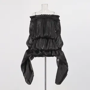 Close-up of a black off-the-shoulder dress with ruffles and asymmetrical flowing sleeves