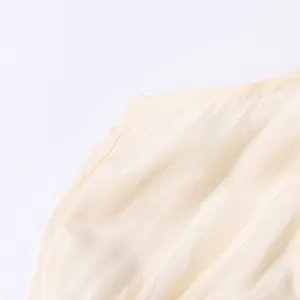 Vue macro détaillée de la texture du tissu crème et des coutures fines d'une robe longue de style