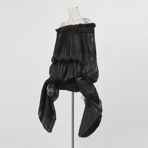 Detail of an off-shoulder black shimmer dress with ruffles and flowing irregular ribbon sleeves.