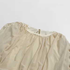 Detailed view of the gathered round neckline on a beige minimalist pleated maxi dress