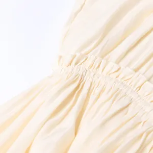 Gros plan détaillé montrant le design délicat de la taille à volants d'une robe longue crème
