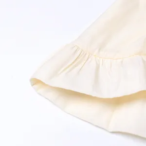 Gros plan sur l'ourlet à volants d'une robe longue crème de style resort.