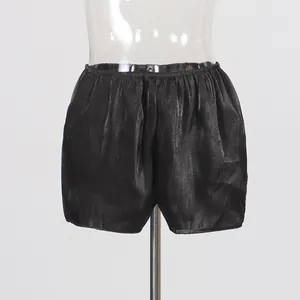 Detailed view of women's black shiny satin resort shorts featuring a comfortable elastic waist