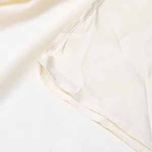 Détail en gros plan d'une robe maxi cape blanche montrant les coutures et la texture