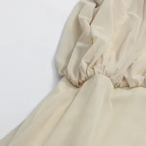 Close-up macro view showing pleated details and lightweight fabric texture on beige dress