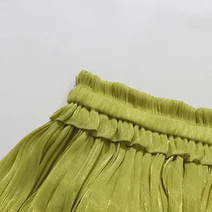 Macro view of olive green pleated dress featuring elastic waist and ruffle design detail