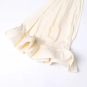 Vue détaillée de l'ourlet à volants crème sur une élégante robe longue de style complexe