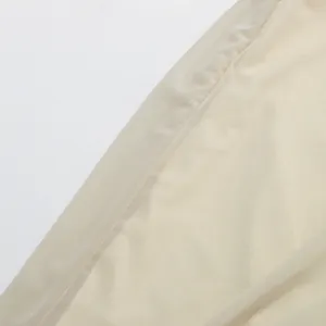 Detailed macro view of delicate beige mesh fabric showing fine stitching on a pleated dress