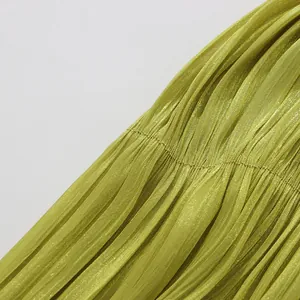 Detailed macro close-up of lime green pleated fabric with a silky metallic sheen finish