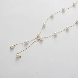 Gros plan d'un élégant collier long doré avec des perles blanches rondes