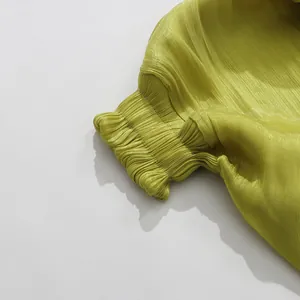 Close-up of shimmery pleated fabric and elastic cuff on lime green resort dress