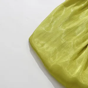 Macro detail of shimmering lime green pleated fabric for a resort style dress.