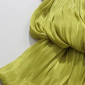 Close-up detail showing the pleated lime green shimmery fabric of the resort dress