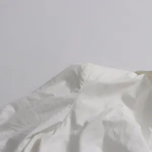 Close-up of the shoulder seam and white cotton fabric texture on a minimalist blouse