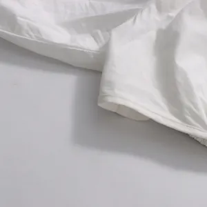 Detailed close-up view of white cotton fabric and stitching on a minimalist long sleeve top.