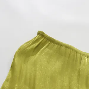 Close-up detail of pleated lime green dress with shimmer texture and elasticated edge