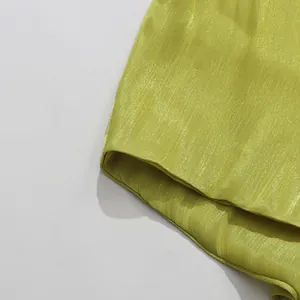 Close-up of shimmering lime green fabric with metallic texture on resort dress.