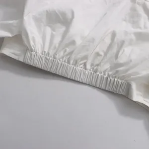 Close-up detail of white long-sleeve top showing the elastic waistband and fabric texture