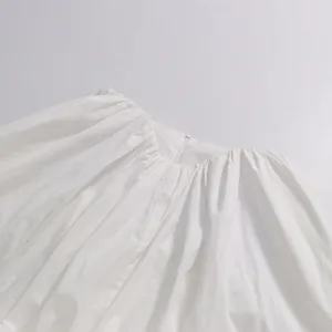 Detailed macro view of an elegant white blouse featuring a gathered neckline and hidden zipper