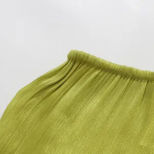 Macro view showing the fine green pleated fabric and elastic waistband of a summer dress