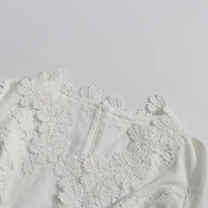 Primer plano de encaje floral 3D calado y detalle de cremallera en vestido blanco