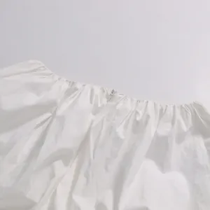 Close-up of white cropped long sleeve top featuring delicate pleats and hidden zipper detail.
