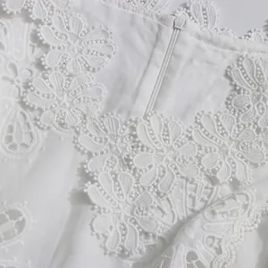 Primer plano de intrincados patrones florales de encaje blanco 3D en un vestido con cuello V.