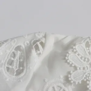 Primer plano del intrincado bordado de encaje blanco calado 3D en vestido palaciego